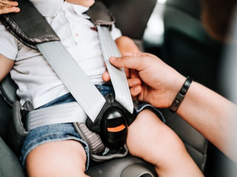 Mains d'un parent ajustant avec précision la tension des sangles du harnais d’un cosy pour bébé afin d'assurer sa sécurité en voiture.