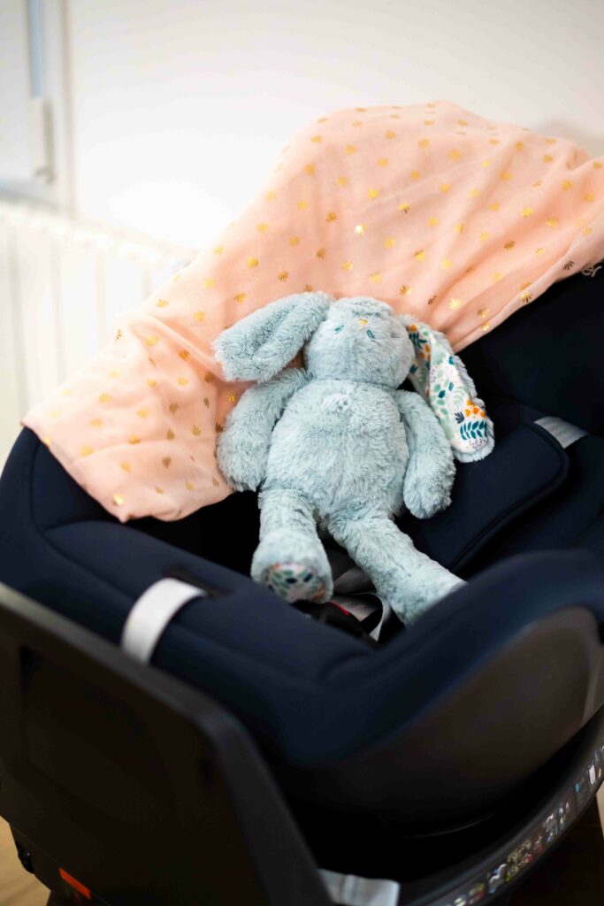 Siège auto de sécurité avec un doudou en peluche installé à l'intérieur, mettant en avant le service de Baby Planner à Caen pour les futurs parents.