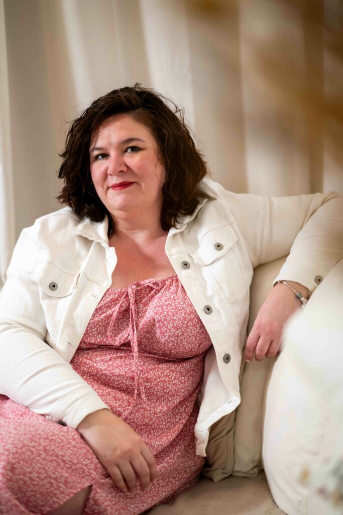 Maureen souriante accoudée au dossier d'un canapé, illustrant la bienveillance des services de baby planning à Caen.